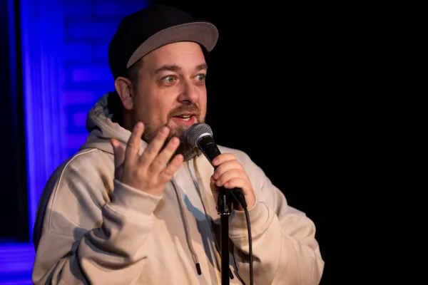 Dan speaking into a microphone under blue stage lights.