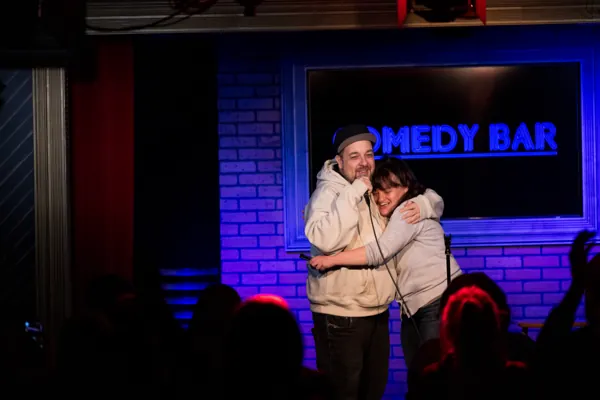 Dan hugging another person on the Comedy Bar stage.